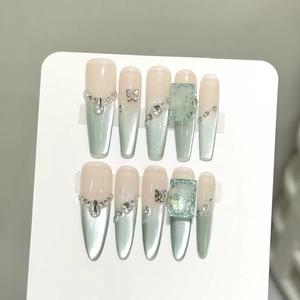 Detailed view of mint green cat-eye press-on nails with butterfly gems and crystals