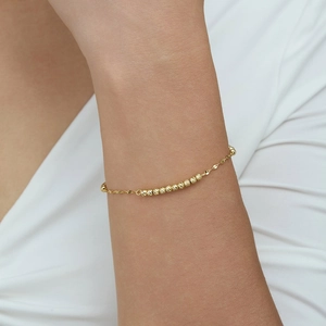 Elegant gold clover bracelet with faceted beads on a delicate chain worn by a woman