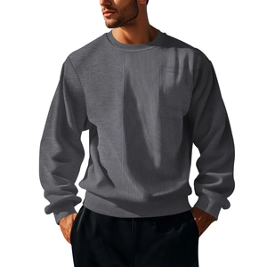 Detail of gray crewneck sweatshirt showing corduroy patchwork texture and chest pocket