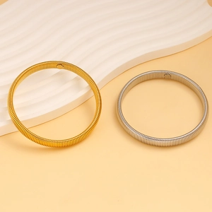 Detailed macro view of gold and silver spring-style metal wire coil bracelets on a tray