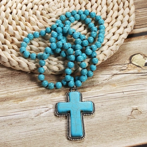 Bohemian 8mm turquoise beaded necklace with vintage cross pendant on natural background