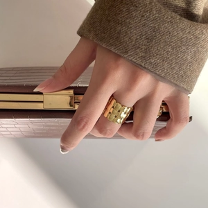 Detailed view of wide gold woven lattice ring worn with luxury alligator leather bag