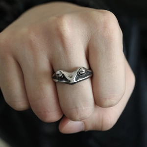 Detailed close-up of retro silver frog ring with realistic eye features on model hand