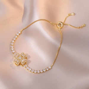 Elegante bracciale a quadrifoglio dorato con zirconi bianchi su raso champagne