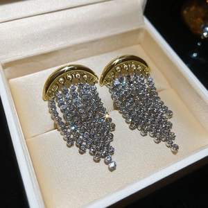 Détail de boucles d'oreilles à pompons scintillants dans un coffret à bijoux premium