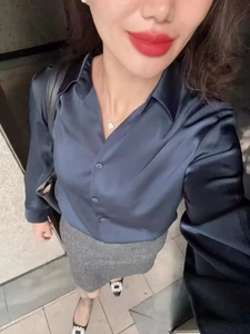 Detail view of a navy blue satin shirt paired with a grey skirt on a model in a selfie style