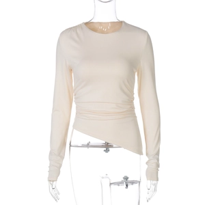 Détail d'un haut beige ajusté à manches longues avec taille froncée et ourlet asymétrique