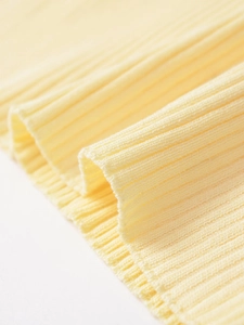 Gros plan détaillé de la texture en maille côtelée jaune montrant élasticité et douceur pure