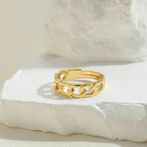 Macro detail of gold chain link open ring on textured white stone background