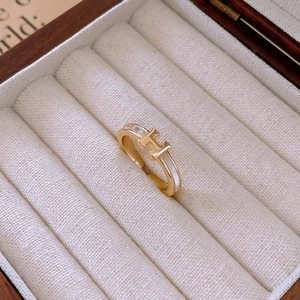 Macro shot of gold-plated H-letter ring with sparkling zircons and white enamel inlay
