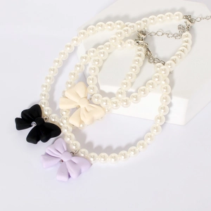 Detailed view of three candy-colored bow pearl necklaces for dogs and cats on white decor