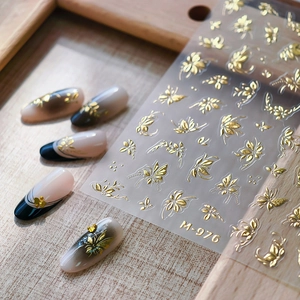 Golden embossed nail stickers M-976 featuring butterfly and leaf motifs on wood background