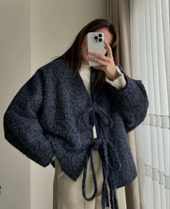 Close-up of fluffy dark grey plush knit cardigan with waist tie and soft texture