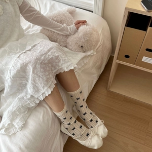 Dettaglio di calze color crema con fiocco abbinate a ballerine bianche e abito di pizzo