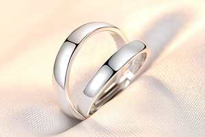 Macro shot of silver minimalist couple rings with crown zircon detail on beige fabric