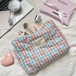 Detail of quilted plaid cosmetic bag with diamond stitching and woven fabric label