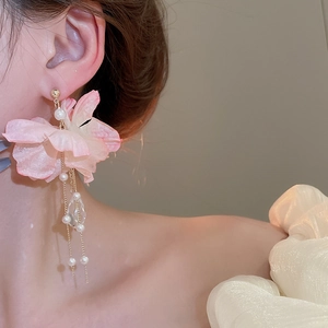 Close-up of pink fabric flower earrings with long pearl tassels and crystal drops