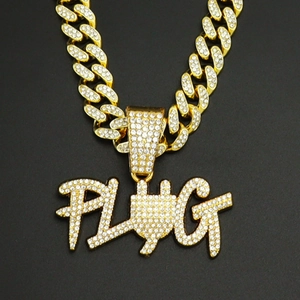 Close-up of gold iced-out PLUG letter pendant with sparkling rhinestones on Cuban chain