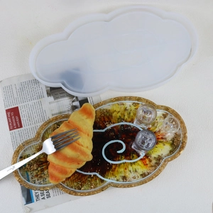 Cloud-shaped silicone resin mold with gold foil tray holding a croissant and fork