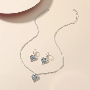 Detailed macro view of vintage heart necklace and earrings with intricate filigree texture