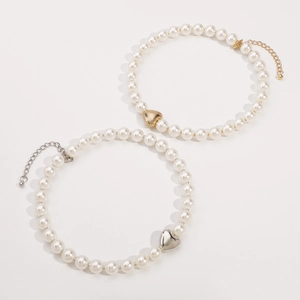Detailed view of elegant pearl necklaces with gold and silver heart pendants on white background