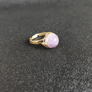 Macro detail of handmade gold wire wrapped ring with a round purple crystal gemstone