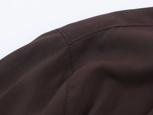 Dettaglio della trama del tessuto e delle cuciture sulla spalla della camicia marrone