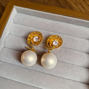 Détail de boucles d'oreilles perles dorées avec spirale ajourée et incrustation zircon