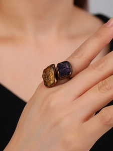 Close-up of vintage bronze adjustable ring featuring raw yellow and purple gemstones