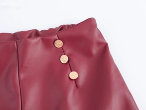 Détail de la taille en cuir PU bordeaux avec bande élastique et trois boutons dorés