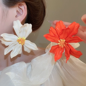 Close-up of large acrylic floral earrings in white and orange on a model