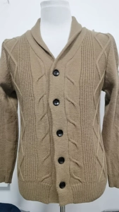 Detail einer braunen Strickjacke mit Zopfmuster, großem Revers und fünf schwarzen Knöpfen