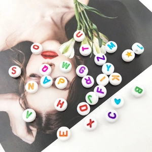 Macro view of white 7mm round resin beads with colorful letters and star patterns for DIY