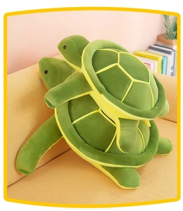 Detail view of two soft green sea turtle plushies in different sizes on a yellow sofa