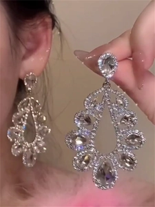 Detailed view of silver hollow teardrop earrings with crystals and fringe design