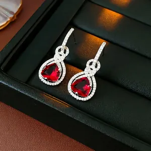 Orecchino d'argento con zircone rosso a triangolo e nodo infinito su pelle nera