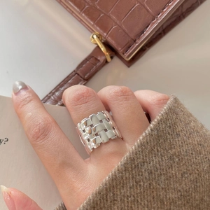 Close-up of wide silver braided texture ring with high polish finish on a model's finger