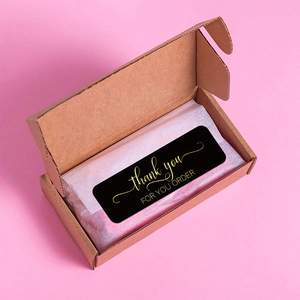 Black and gold Thank You for Your Order stickers on white wrapping paper in a gift box