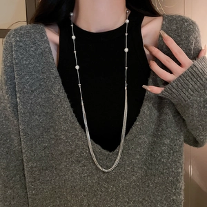 Detailed view of multilayer long pearl necklace with silver tassels worn on a model