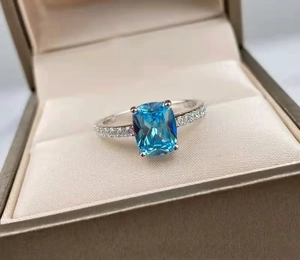 Close-up of a blue cushion-cut zircon ring in a gift box with side stone details