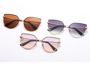 Close-up of cat-eye sunglasses in brown, purple and pink gradients with gold metal frames