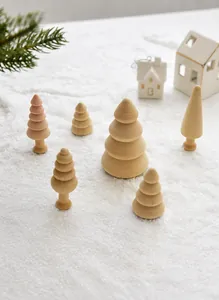 Flat lay of assorted natural wood mini Christmas tree ornaments on artificial snow