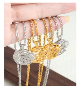 Detail of sun face pendant necklaces in gold and silver held by hand with twisted chain
