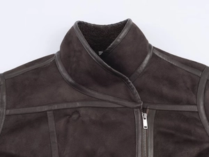 Detail of dark brown shearling jacket featuring leather trim and metal zipper close-up