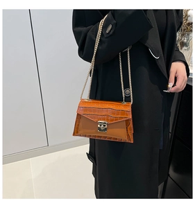 Detail showing brown crocodile pattern leather surface and gold chain strap of the bag