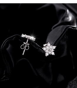 Macro shot of silver snowflake earrings with sparkling zirconias on black leather