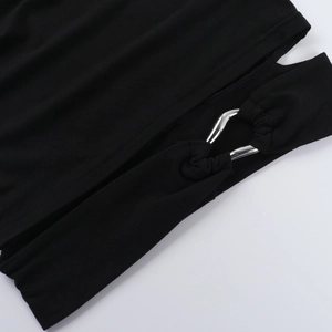 Dettaglio ravvicinato della maglia nera con anello in metallo argento e tagli cut-out