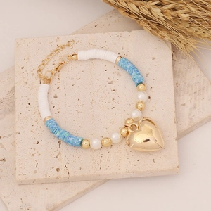 Detail of bohemian bracelet with golden heart pendant and blue clay beads