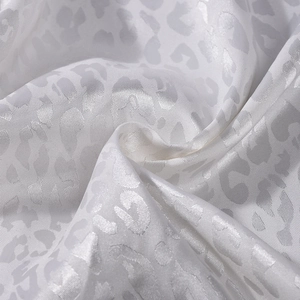 Detailed macro view of white satin fabric with elegant leopard jacquard texture and shine