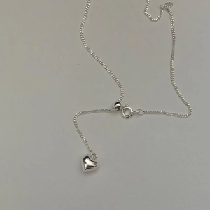Detail of silver heart necklace with adjustable slider clasp on minimalist background